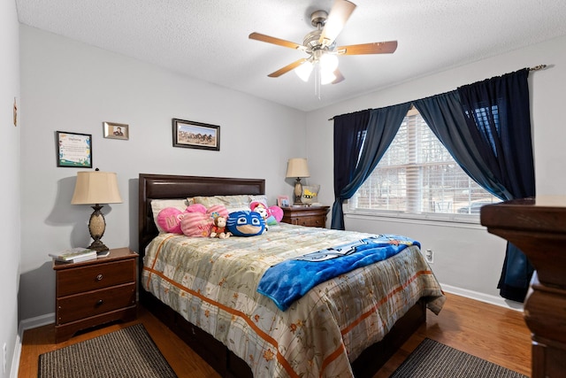 bedroom with ceiling fan, wood-type flooring, and a textured ceiling