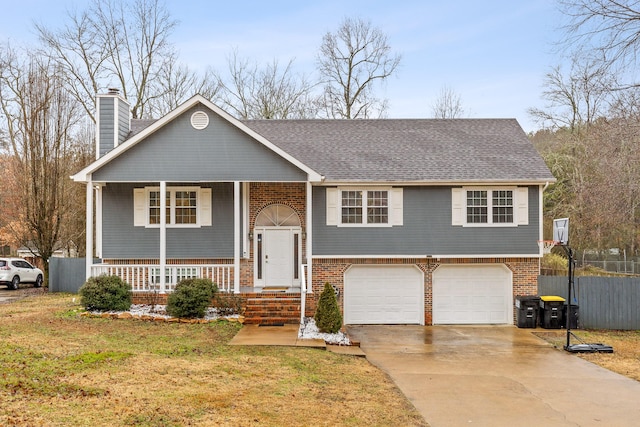 raised ranch featuring a garage, a front yard, and covered porch