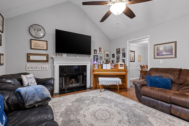 living room featuring lofted ceiling, wood-type flooring, a tile fireplace, and ceiling fan