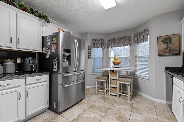 kitchen with white cabinetry, stainless steel appliances, a textured ceiling, and light tile patterned floors