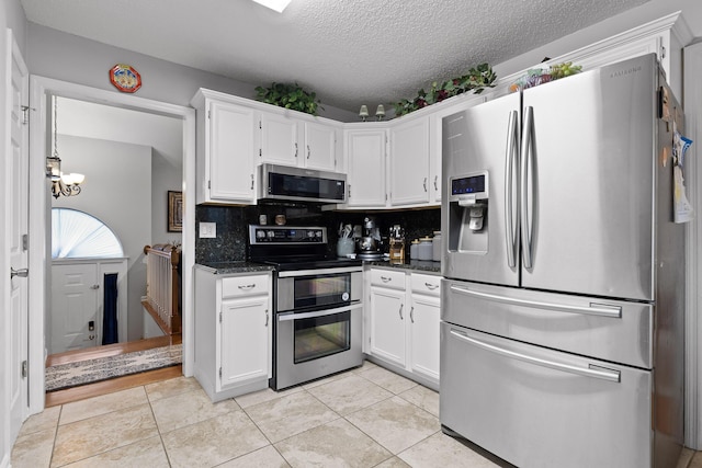 kitchen with white cabinetry, appliances with stainless steel finishes, light tile patterned floors, and backsplash