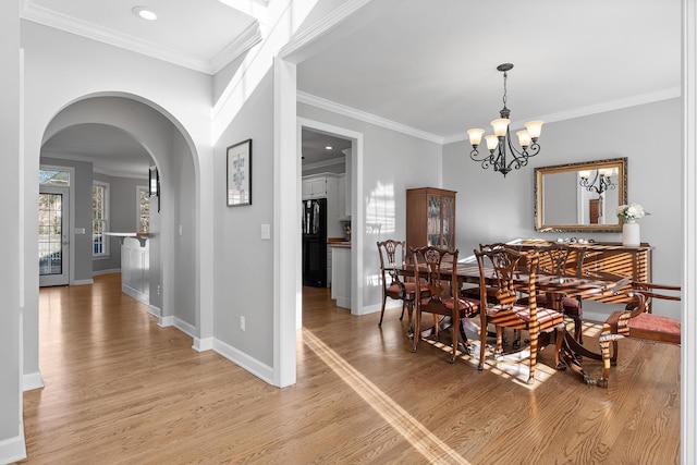 dining room with crown molding, a chandelier, and light wood-type flooring