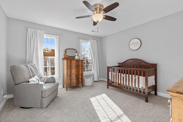 bedroom with a nursery area, carpet flooring, and ceiling fan