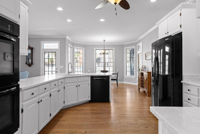 kitchen featuring sink, hardwood / wood-style floors, ornamental molding, black appliances, and white cabinets