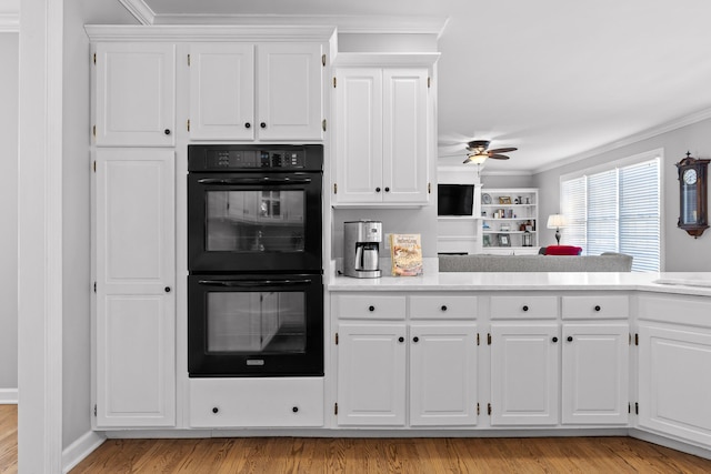 kitchen featuring white cabinetry, black double oven, ceiling fan, light hardwood / wood-style floors, and crown molding