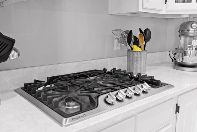 details with stainless steel gas stovetop and white cabinets