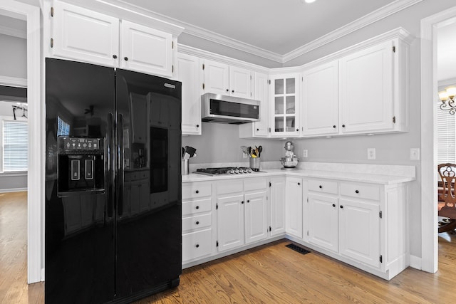 kitchen with ornamental molding, appliances with stainless steel finishes, white cabinets, and light hardwood / wood-style flooring