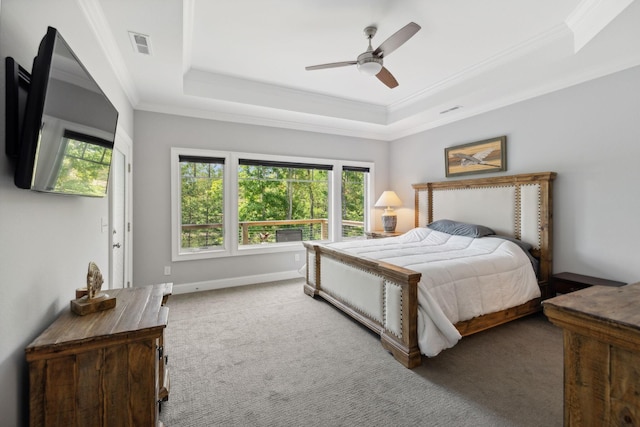 carpeted bedroom with crown molding, a raised ceiling, and multiple windows