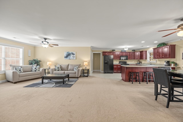 carpeted living room featuring sink, crown molding, and ceiling fan