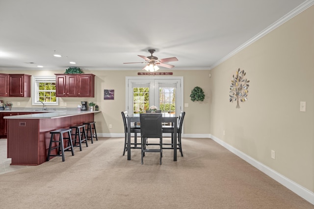 carpeted dining room featuring sink, crown molding, and ceiling fan