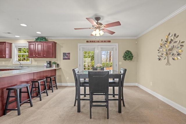 carpeted dining area with sink, ornamental molding, and ceiling fan