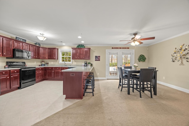 kitchen with a kitchen bar, ornamental molding, a center island, light colored carpet, and black appliances