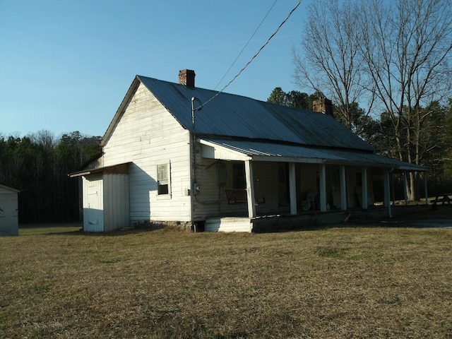 view of side of property with a yard and covered porch