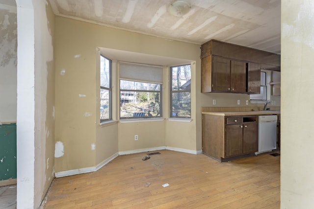 kitchen with dark brown cabinets, white dishwasher, sink, and light hardwood / wood-style flooring