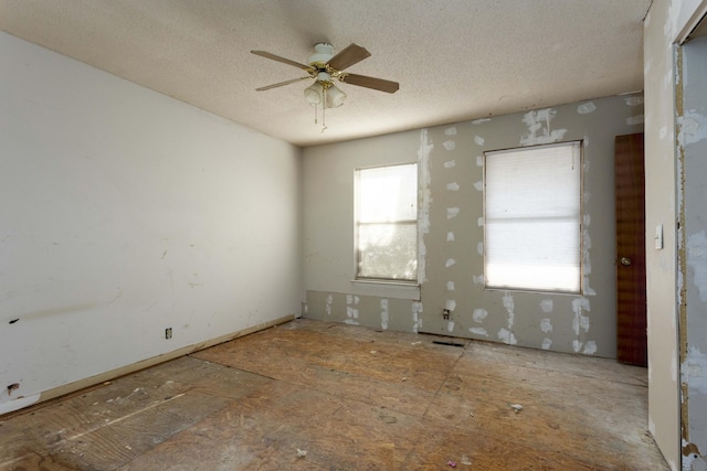 empty room with ceiling fan and a textured ceiling