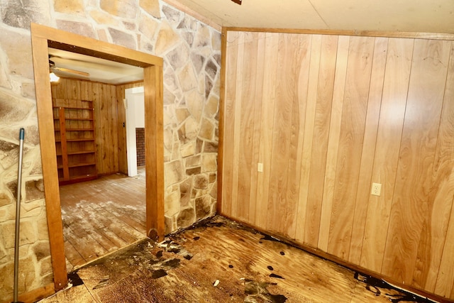 interior space with ceiling fan and wood walls