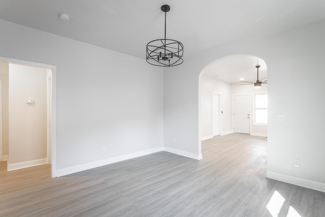 unfurnished room featuring ceiling fan with notable chandelier and light hardwood / wood-style flooring