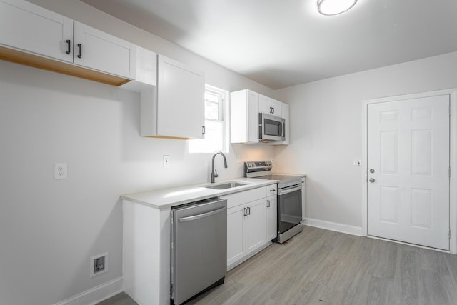 kitchen with sink, light hardwood / wood-style flooring, stainless steel appliances, and white cabinets