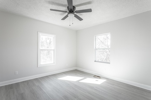 empty room with ceiling fan, dark hardwood / wood-style floors, and a textured ceiling