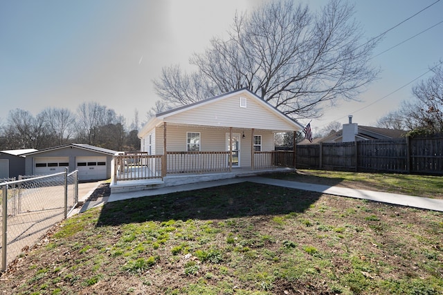 bungalow featuring an outbuilding, a garage, a front lawn, and covered porch