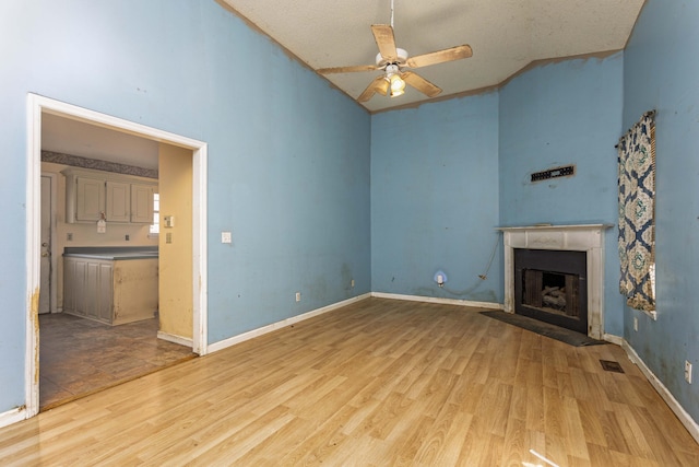 unfurnished living room with ceiling fan, high vaulted ceiling, and light wood-type flooring