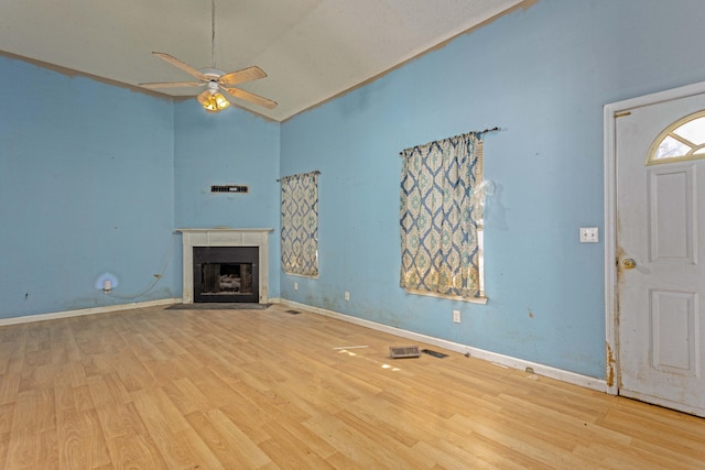 unfurnished living room with ceiling fan, vaulted ceiling, and light wood-type flooring