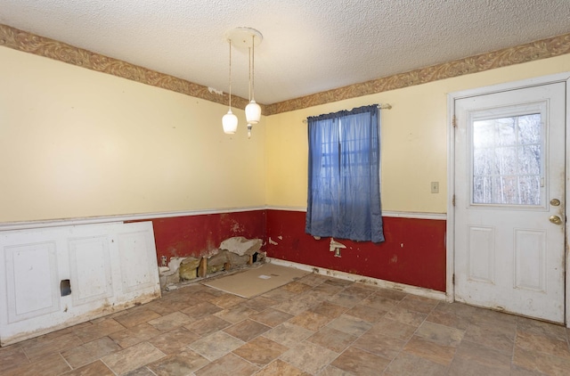 unfurnished dining area featuring a textured ceiling