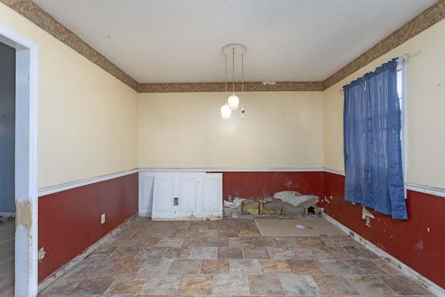 unfurnished dining area featuring a textured ceiling