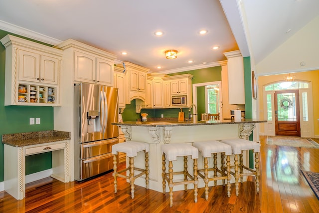 kitchen featuring ornamental molding, appliances with stainless steel finishes, cream cabinetry, and dark stone countertops