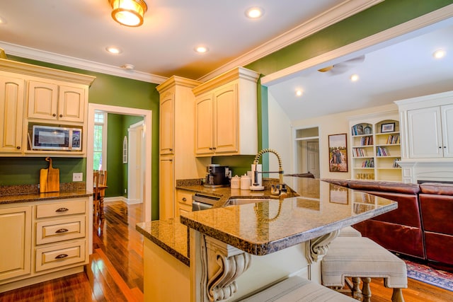 kitchen with a breakfast bar, sink, appliances with stainless steel finishes, dark hardwood / wood-style flooring, and dark stone counters