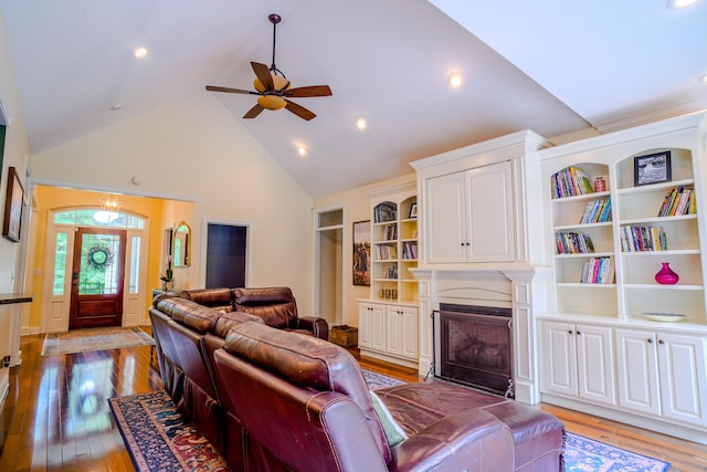 living room featuring high vaulted ceiling, built in features, light hardwood / wood-style floors, and ceiling fan