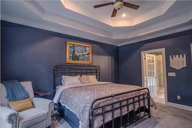 carpeted bedroom with ceiling fan, ensuite bath, and a tray ceiling