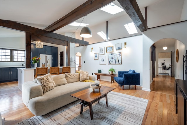 living room featuring vaulted ceiling with beams and light wood-type flooring