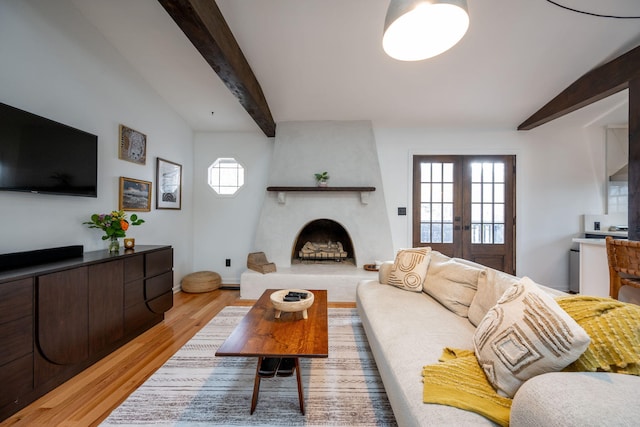 living room with lofted ceiling with beams, plenty of natural light, light hardwood / wood-style floors, and french doors