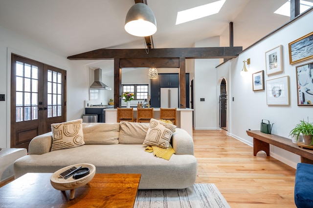 living room featuring french doors, lofted ceiling with skylight, and light hardwood / wood-style floors