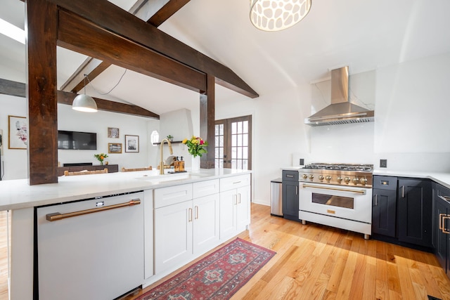 kitchen with dishwasher, sink, white cabinets, high quality range, and wall chimney exhaust hood