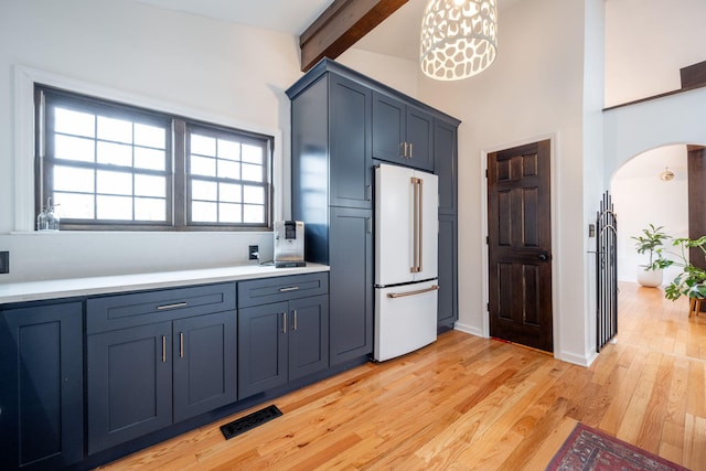 kitchen with pendant lighting, high end white fridge, blue cabinets, beamed ceiling, and light wood-type flooring