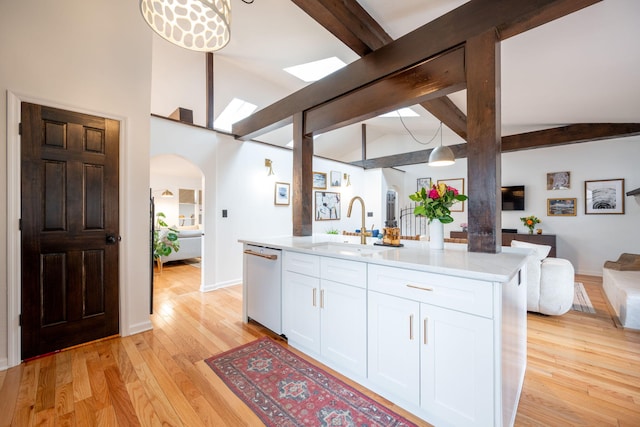 kitchen with sink, white cabinetry, a kitchen island with sink, white dishwasher, and decorative light fixtures