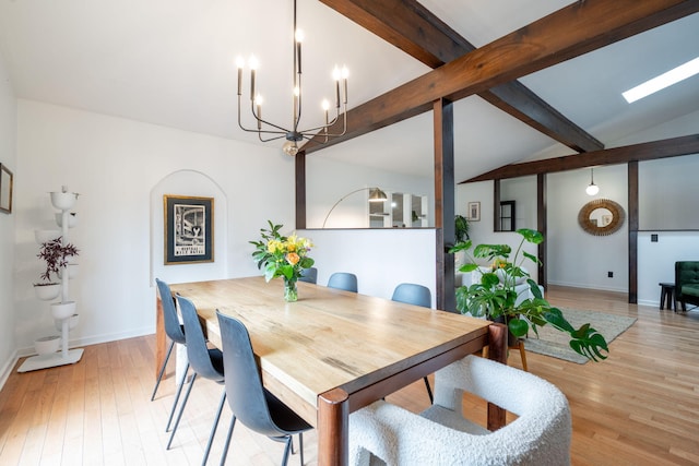 dining area with lofted ceiling with beams, an inviting chandelier, and light hardwood / wood-style flooring