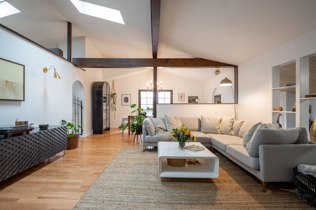 living room featuring vaulted ceiling with skylight, light hardwood / wood-style floors, and a notable chandelier