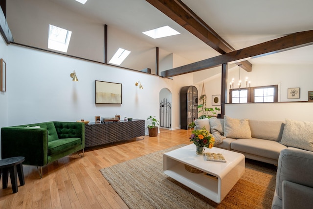 living room featuring vaulted ceiling with beams, a notable chandelier, and light wood-type flooring