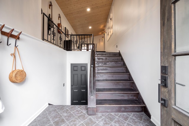 staircase featuring a towering ceiling, wooden ceiling, and tile patterned floors