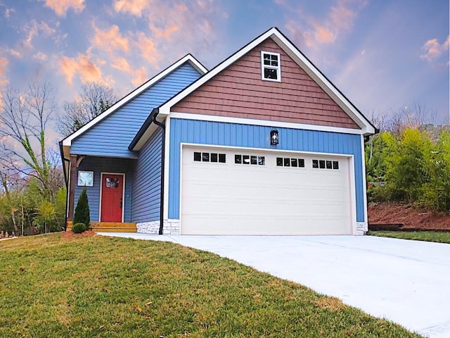 view of front of house featuring stone siding, a lawn, concrete driveway, and a garage