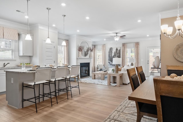 kitchen with light stone counters, hanging light fixtures, a breakfast bar area, and white cabinets