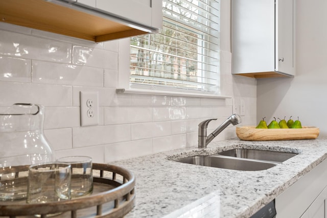 kitchen featuring light stone counters, sink, decorative backsplash, and white cabinets