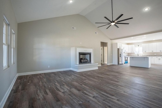 unfurnished living room featuring ceiling fan, high vaulted ceiling, dark hardwood / wood-style floors, and sink