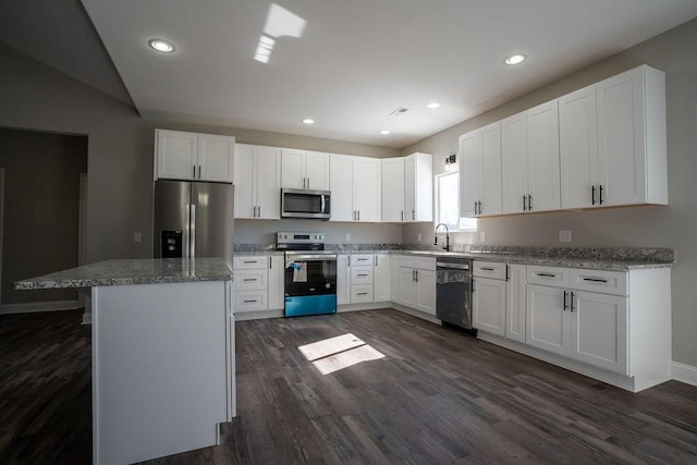 kitchen with sink, a kitchen island, white cabinets, and appliances with stainless steel finishes