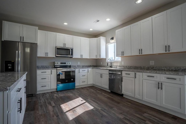 kitchen featuring light stone counters, stainless steel appliances, dark hardwood / wood-style floors, and white cabinets