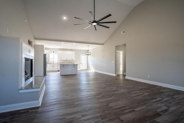 unfurnished living room featuring high vaulted ceiling, dark hardwood / wood-style floors, and ceiling fan