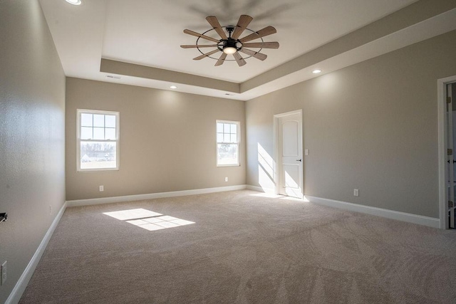 carpeted empty room with ceiling fan and a raised ceiling